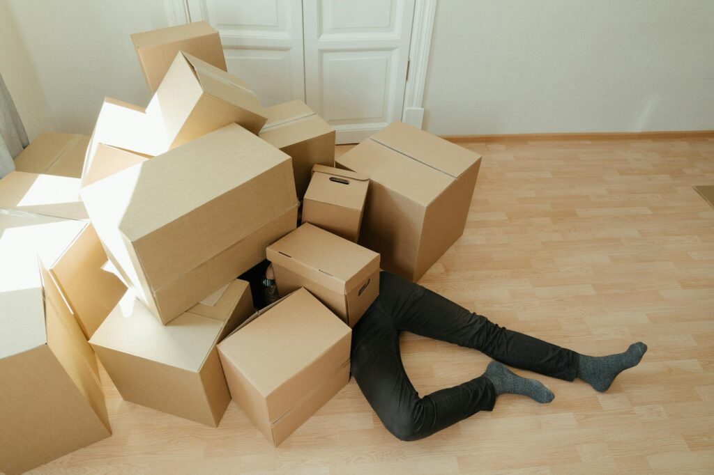 person overwhelmed by large inventory boxes in small space