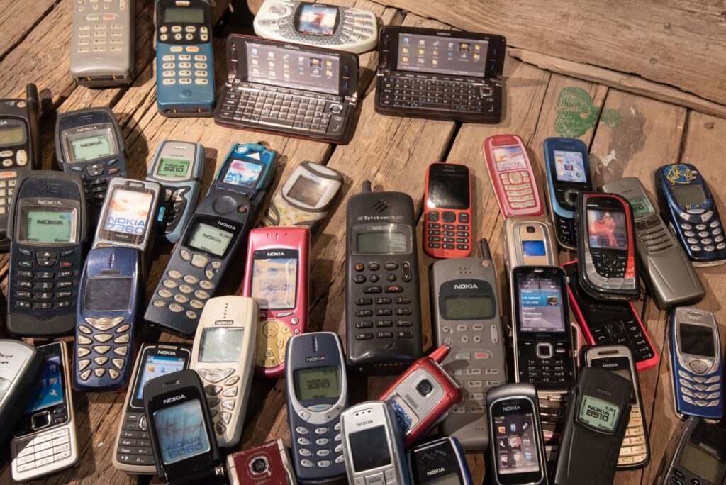 Modern smartphone, flip phone, and older cell phones being prepared for sale on eBay